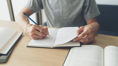 Üniversite ya da üniversite öğrencisi evde okuyor, öğreniyor ya da ders kitabı okuyor. Başarı fikri, kendi kendine öğrenme ve eğitim. Eğitim geliştirme ve bilgi geliştirme kavramı