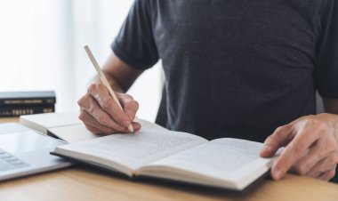 Üniversite öğrencisi ders çalışmak ya da kitap öğrenmek için dizüstü bilgisayar kullanıyor, evde ders kitabı okuyor. Bilgi ve beceri eğitimi evde çevrimiçi. Eğitim ve bilişsel başarı fikri
