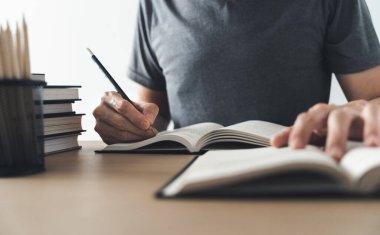 Üniversite öğrencisi evde ders çalışıyor ya da kitap öğreniyor, yazıyor ya da kitap okuyor. Bilgi ve beceri eğitimi evde çevrimiçi. Eğitim ve bilişsel başarı fikri