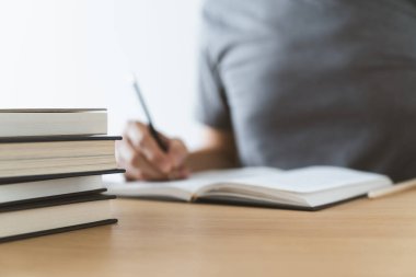 Üniversite öğrencisi evde ders çalışıyor ya da kitap öğreniyor, yazıyor ya da kitap okuyor. Bilgi ve beceri eğitimi evde çevrimiçi. Eğitim ve bilişsel başarı fikri