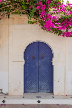 Geleneksel mavi kapılı, desenli fayanslar ve pembe çiçekli, Hara Sghira Er Riadh - Tunus 'tan Djerbahood