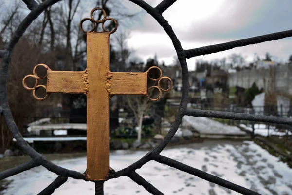 Wrought iron cross painted in golden paint on the gates of the cemetery