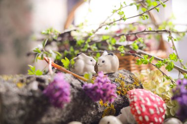 Bıldırcın yumurtalarının, bahar çiçeklerinin, yeşil yosunların ve eski odunların arasında küçük paskalya tavşanları. seramik antika tavşanlar, kırmızı mantar, sineklik, fantezi duvar kağıdı