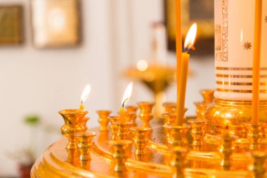 Kandil 'e yakın çekimde kilise mumları yakmak. Görünür simgelerin arkasında