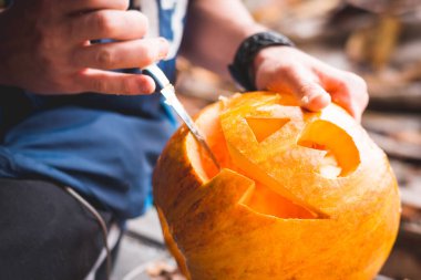 Adam Cadılar Bayramı için balkabağından fener yapıyor. Cadılar bayramı için balkabağı oymaya yakın dur.