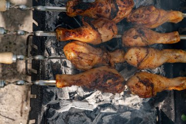 Chicken shanks on skewers on grill, grilling. clipart