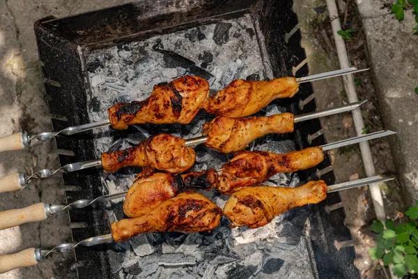 stock image Chicken shanks on skewers on grill, grilling.
