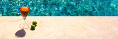 Havuzda bir bardak pembe şarap ve sarı güneş gözlüğü. Yaz tatili kavramı.