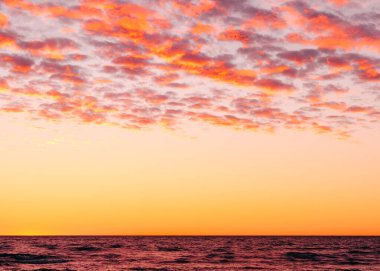 Deniz üzerinde pembe ve mor bulutlarla dramatik günbatımı gökyüzü