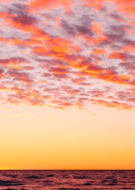 Deniz üzerinde pembe ve mor bulutlarla dramatik günbatımı gökyüzü