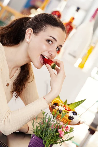 在咖啡店 冰激凌店和糕点店 年轻美丽的微笑的女人 一杯水果沙拉 上面有冰激凌 女孩吃冰淇淋 水果和草莓的肖像 — 图库照片