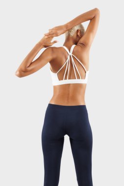 Spor salonu, kollarını ve sırtını uzatan kadın, spor giyim dalında Afrikalı Latin Amerikalı bayan sporcu, spor salonunda egzersiz yapan kadın, arka planda izole bir şekilde görülen, sağlığını iyileştirmek için spor yapıyor.