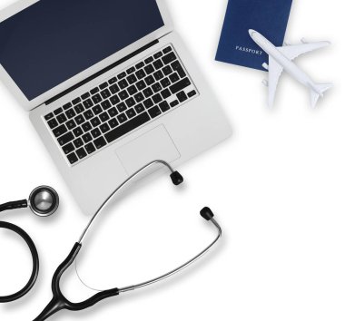 Pasaport, uçak, bilgisayar ve steteskop manzarası beyaz arka planda izole edilmiş, sağlık sigortası seyahat konsepti ister yaz tatili ister iş gezisi olsun. Sağlık ve Güvenlik