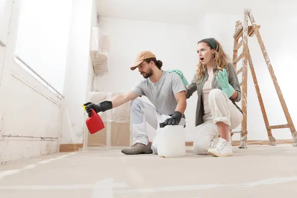 Stock image Concerned Woman and Partner young couple using professional products for DIY mold remediation and Repainting in Home Renovation Project. Cleaning and Treatment for healthier living environment.