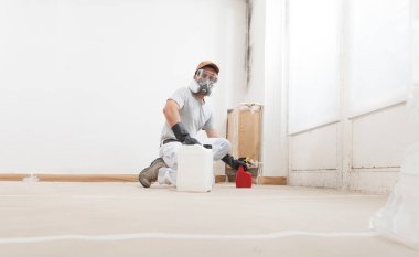 Erkek İşçi Sprey Ürünleri Duvar 'da kalıp çıkarmak için, koruyucu eldivenler ve bir Solunum maskesi takıyor, sprey şişe kullanıyor. Ev Yenileme Alanındaki Ev Boyama İçin Küflü Duvarın Düzeltilmesi