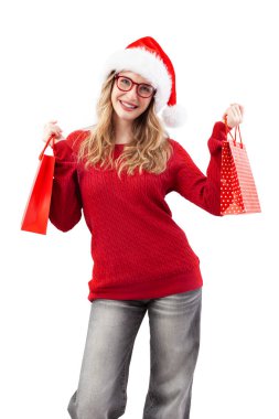 Neşeli sarışın bir kadın kırmızı gözlük ve Noel Baba şapkası takıyor, alışveriş torbaları tutuyor ve büyük mavi gözleriyle kameraya bakıyor. Çevrimiçi alışveriş ve bir gözlükçünün ya da internet mağazasının teklifleri