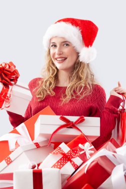 Noel hediyesi, alışveriş arabası hediye kutularıyla dolu mutlu kadın Noel Baba şapkası takıyor, beyaz arka planda soyutlanmış. Satılık mağaza promosyonları ya da online alışveriş reklamları için mükemmel.