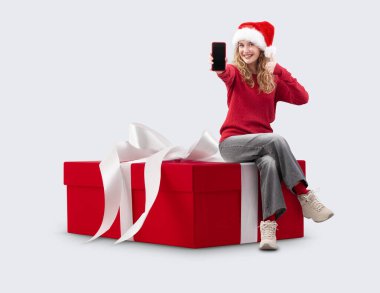 Noel hediyesi kutulu kadın akıllı telefonu gösteriyor ve Noel Baba şapkası takıyor. Ticari tabela şablonu. Mağaza ve alışveriş merkezi Billboard en iyi anlaşmaları ve satışı, tatil teklifi veya çevrimiçi alışveriş afişi