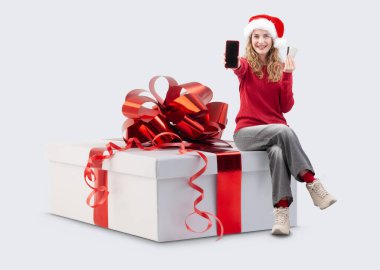 Elinde Noel hediyesi olan kadın akıllı telefonu ve kredi kartını gösteriyor. Ticari tabela şablonu. Mağaza ve alışveriş merkezi Billboard en iyi anlaşmaları ve satışı, tatil teklifi veya çevrimiçi alışveriş afişi