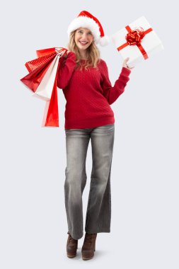 Mutlu Noeller Noel Baba şapkası takan kadın hediye kutusu ve kırmızı alışveriş torbaları tutuyor. Satışa sunulacak resim promosyonlar, çevrimiçi alışveriş, reklam afişi, poster veya hediye kartı, izole edilmiş arka plan