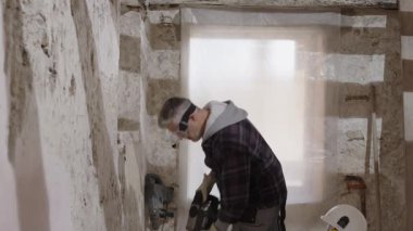 İnşaat işçisi güvenlik kaskı ve kulaklık takıyor, şapkayı yumrukla vuruyor, güven ve koruma gösteriyor, güvenliği ilk ve kişisel koruma ekipmanlarını vurguluyor, PPE