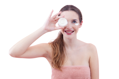 Gülümseyen genç bir kadın cilt nemlendirici sürüyor ve kameraya bakarken bir kavanoz krema tutuyor. Cilt bakımı ve güzellik anlayışı. Arka planda izole edilmiş. Yüz bakımı, makyaj ve sağlıklı cilt