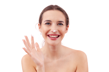 Cilt nemlendirici kremi sürerken gülümseyen genç bir kadın. Parmağında ve burnunun ucunda güzellik kremi var. Arka planda izole edilmiş. Yüz bakımı, makyaj ve sağlıklı cilt