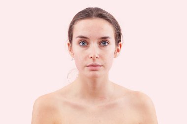 Gerçek deri dokusu, yüz hatları, sivilceleri, sivilceleri ve lekeleri olan makyajcı kadın yok. Cilt bakımı ya da güzellik tedavisinden önce hakiki kadın yüzü. Kameraya bakıyorum, pembe arka planda izole edilmiş.. 