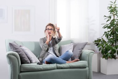 Yanında akıllı telefon olan akıllı gözlüklü genç bir kadın. Ekrana dokunur ve sanal ekranda dijital içerikle etkileşime girer gibi ileriye bakar. Gelecekçi teknoloji konsepti