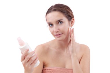 Gülümseyen genç bir kadın yüzünü pamuk ped ve mikiler suyuyla temizliyor. Cilt rutini, makyaj çıkarma, taze sağlıklı deri. Beyaz arka plan, güzellik ve hijyen kavramına izole edilmiş.