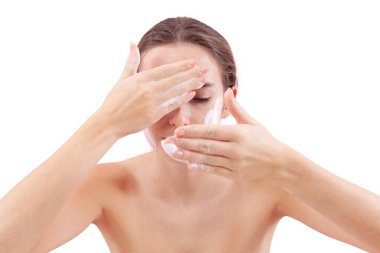 Yüzünü köpük temizleyiciyle temizleyen, ellerini köpükle kaplayan ve cildine süren genç bir kadın. Temiz ve sağlıklı yüz için cilt rutini. Beyaz arka planda izole edilmiş, akne bakımı