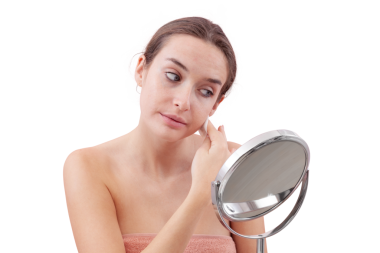 Genç bir kadın, aynanın önünde yüzünü pamuk pedlerle temizliyor ve suyu bodruma indiriyor. Cilt rutini, makyaj çıkarma, taze sağlıklı deri. Beyaz arka plan, güzellik ve hijyen kavramına izole edilmiş.