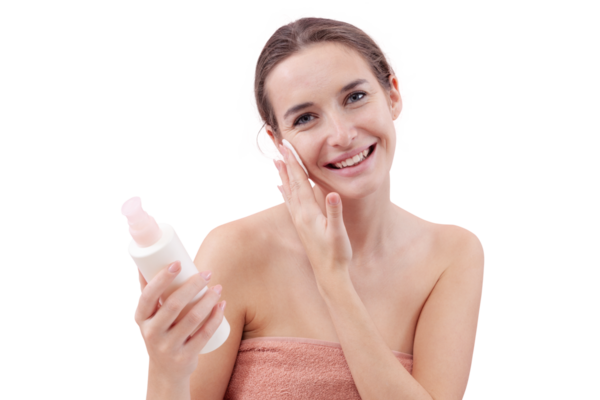 Gülümseyen genç bir kadın yüzünü pamuk ped ve mikiler suyuyla temizliyor. Cilt rutini, makyaj çıkarma, taze sağlıklı deri. Beyaz arka plan, güzellik ve hijyen kavramına izole edilmiş.