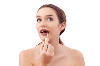 Dudak fırçası aplikatörüyle dudaklarına ruj süren genç bir kadın makyaj rutininin bir parçası olarak. Pürüzsüz, kusursuz bir ten. Beyaz arka planda izole edilmiş güzellik konsepti, kameraya bakıyor.