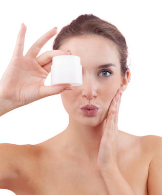 Makyajlı genç bir kadın, yüzüne bir öpücük üflerken plastik bir makyaj kremi tutuyordu. Cilt bakımı ve güzellik tedavisi rutin konsepti. Beyaz arkaplanda izole