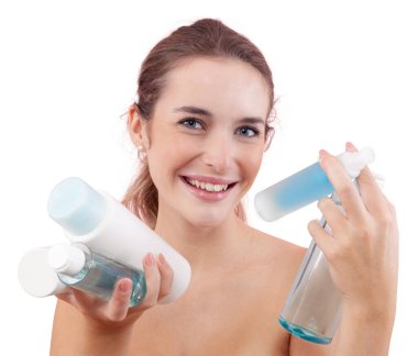 Elinde mikiler suyu ve duş jeli de dahil olmak üzere çeşitli cilt bakımı şişeleri ve banyo ürünleri tutan gülümseyen genç bir kadın. Günlük güzellik, temiz cilt ve hijyen konsepti. Beyaz arkaplanda izole