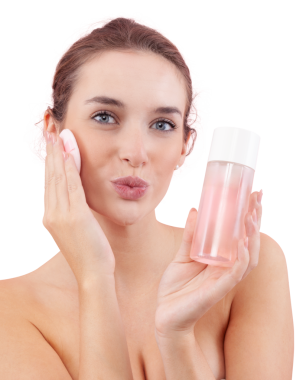 Makyajı pamukla kaldıran, kameraya öpücük gönderen ve mikiler su şişesini tutan genç bir kadının portresi. Cilt rutini ve yüz temizleme. Beyaz arka planda izole edilmiş güzellik konsepti