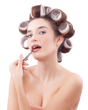 Makyaj, mavi gözleriyle kameraya bakarken saç bigudiyle ruj süren gülümseyen genç kadın. Saç stili, makyaj, güzellik ve kozmetik anlayışı. Beyazda izole edilmiş