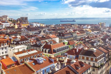 Lisboa şehir merkezinin çatısı. Lizbon, Portekiz Alfama bölgesinde ufuk çizgisi. Tepeleri, kırmızı çatıları ve renkli evleri olan eski şehir manzarası. Tagus Nehri 'nde büyük bir gemi. Şehrin havadan görünüşü