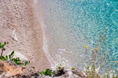 Deniz ve kayaların arka planı. Bitkiler, taşlar, uçurumlar ve kumlarla dolu güzel bir hava manzaralı plaj. Cennet kumsalı. Boş kıyı şeridi. Cennet tatili.