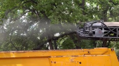 Yol tamir makinesi asfaltı alır ve kamyona yükler.