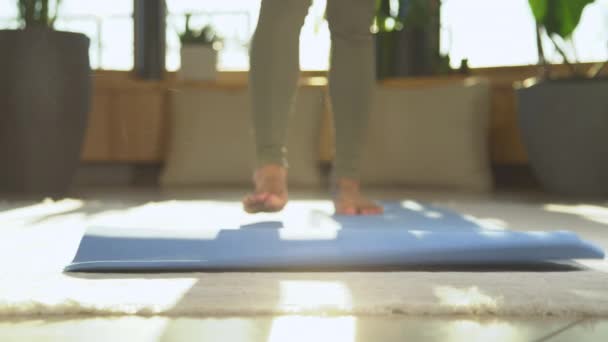 慢动作 无法辨认的女人打开瑜伽垫 走向镜头 女性在室内休闲活动中锻炼垫 准备冥想和放松 — 图库视频影像