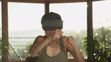 Genç Asyalı kadın evde sanal boks yapıyor ve modern VR gözlükleri kullanıyor. Spor ve sanal gerçeklik kavramını bağlamak. Asyalı kadın evde boks egzersizleri yapıyor. Fütürist teknolojik aletlerle..