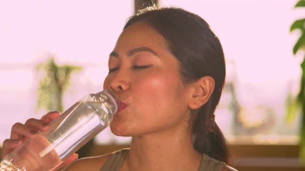漂亮的亚洲女人在家里做了大量的运动后 可以喝水 在家庭体育活动中休息一下的年轻女性 喝清水解渴 — 图库视频影像