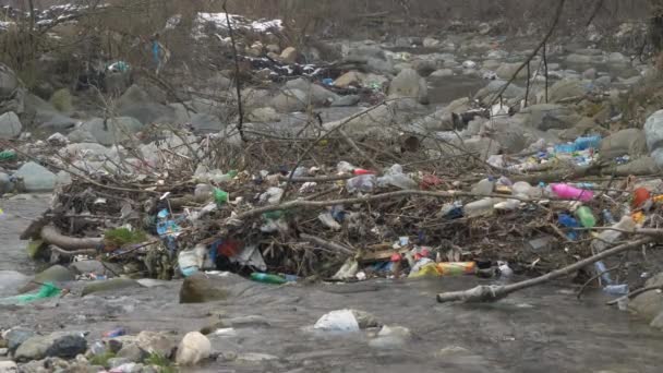 Static Shot 破片とプラスチックごみの混合物に囲まれた流れる川 河川で発生する大量のプラスチック廃棄物は環境問題を引き起こし 環境意識教育の必要性が高まっています — ストック動画