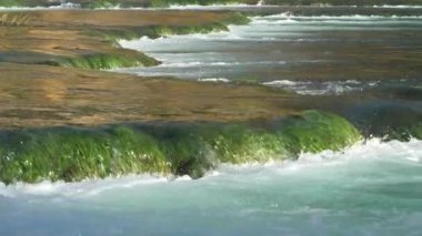 Küçük şelaleler oluşturan yeşil çağlayanın üzerinden akan güzel Krka nehrinin ayrıntılı görüntüsü. Huzurlu ve pitoresk doğal manzara korunan bölgelerde turizm için açıldı