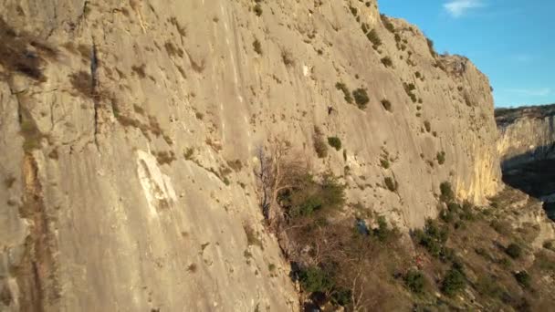 太陽の光が岩壁に登り 男性登山者に近づいて飛んでいます 美しく絵のような環境でアドレナリン屋外活動 壁の真ん中でロッククライマー塩 — ストック動画