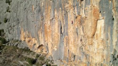 Güneşli duvarda yükselen kadın kaya tırmanışçısıyla muhteşem bir manzara. Nefes kesici ve pitoresk çevrede adrenalin aktivitesi. Kireçtaşı duvarına tırmanan bir dağcı..