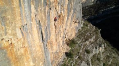 Yükselen genç kadın kaya tırmanıcısıyla muhteşem güneş ışığıyla aydınlatılmış kireç taşı duvarı. Nefes kesici ve pitoresk bir çevrede adrenalin aktivitesi. Kanyon duvarına tırmanan bir dağcı..