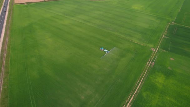 Aerial Blå Traktor Med Landbruksmaskiner Som Vanner Landbruksjord Nær Hovedveien – stockvideo